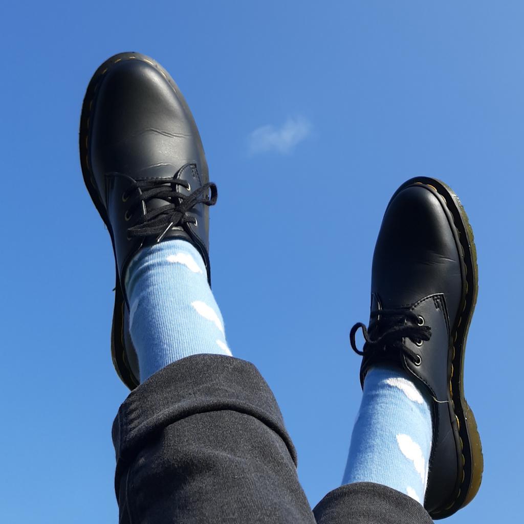 Chaussettes fantaisie bleu ciel à motifs nuages blancs marque Cassepieds sur modèle pieds en l'air fond ciel bleu